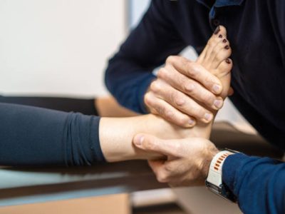 Professional physiotherapist providing manual therapy for foot and ankle, focusing on patient's joint mobility and pain relief.